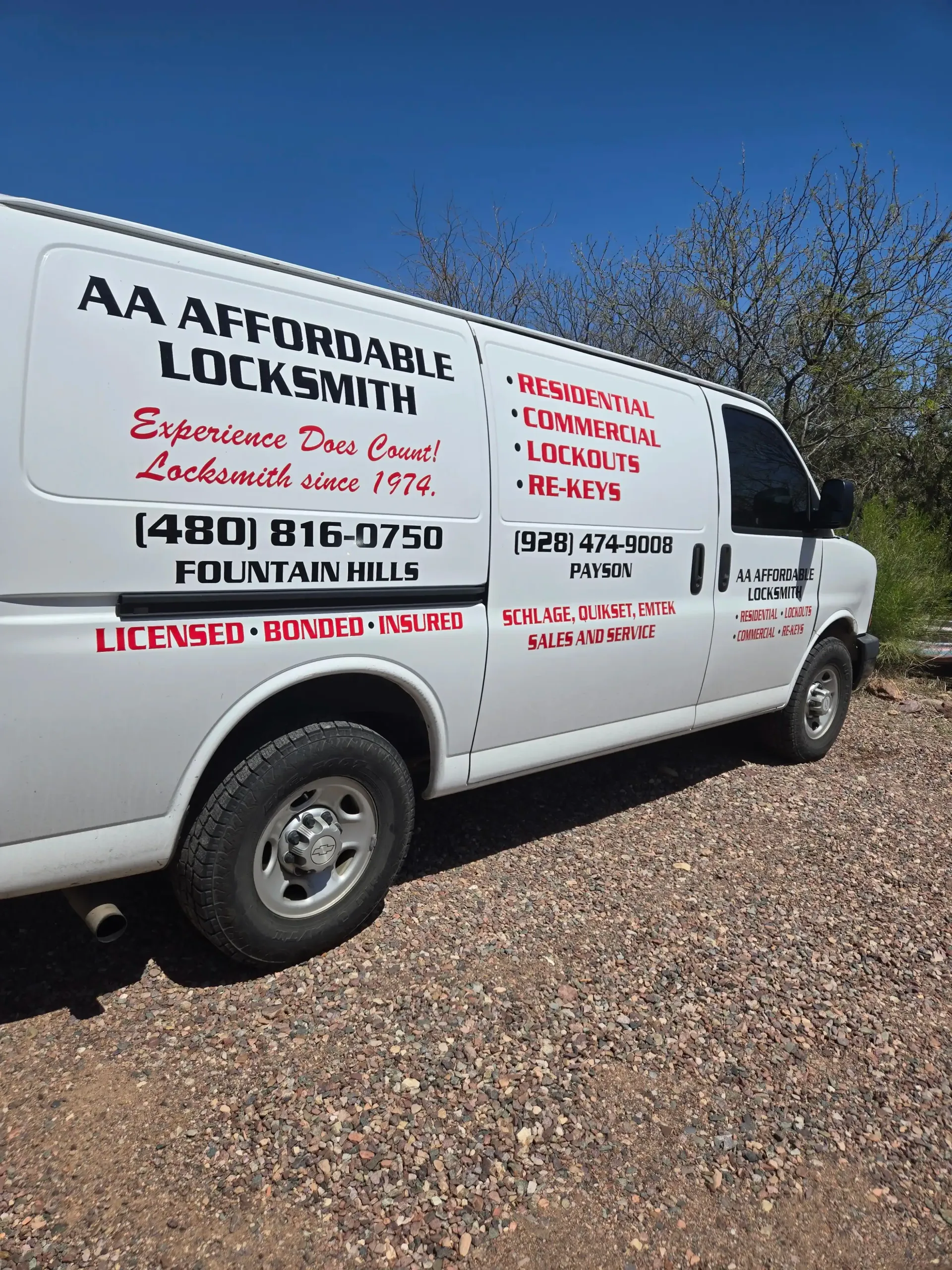 White AA Affordable Locksmith van parked on gravel under a blue sky, with company phone number and lettering visible