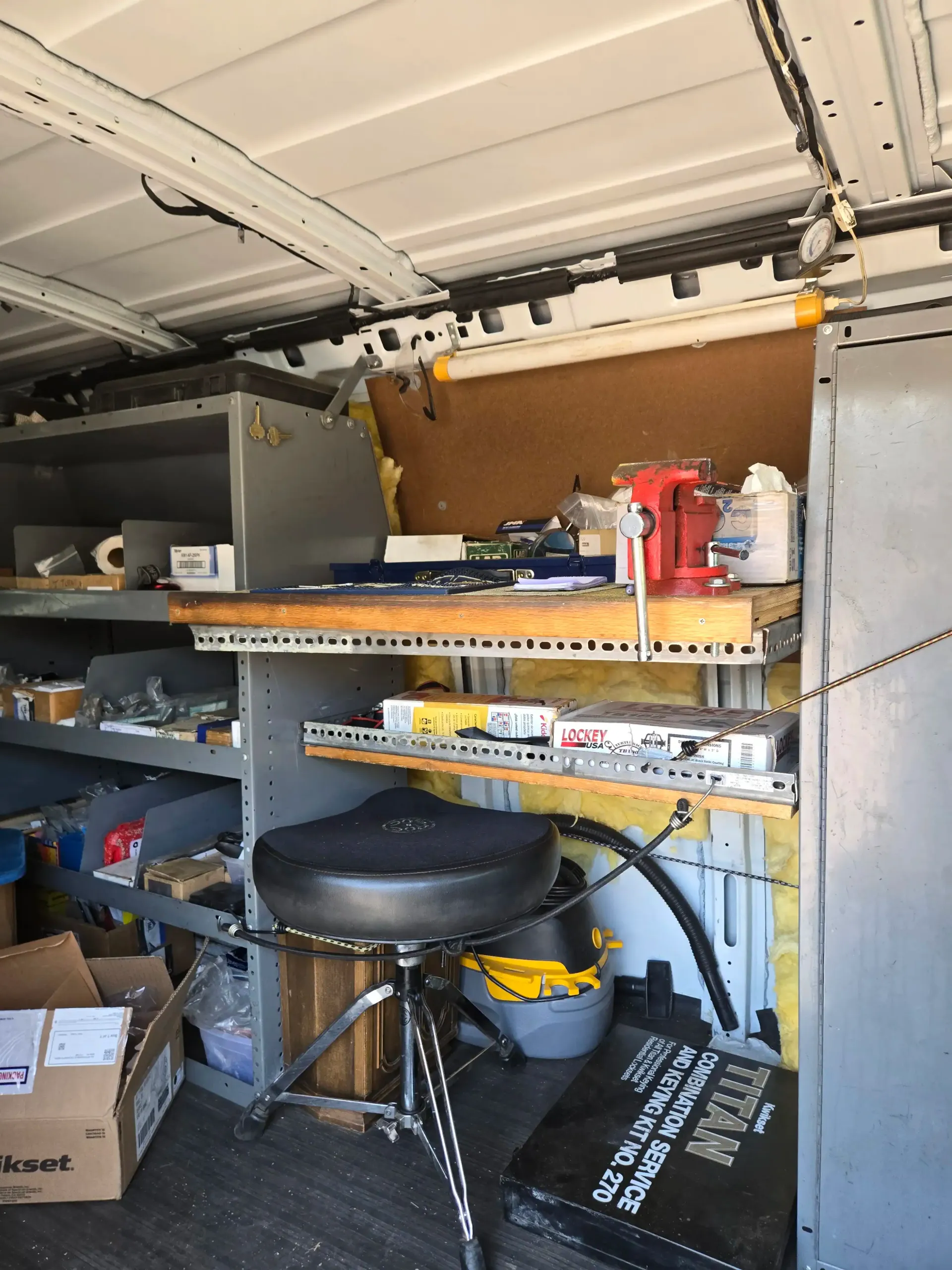 Organized garage workshop shelves with tools, boxes, and a stool under an open garage door