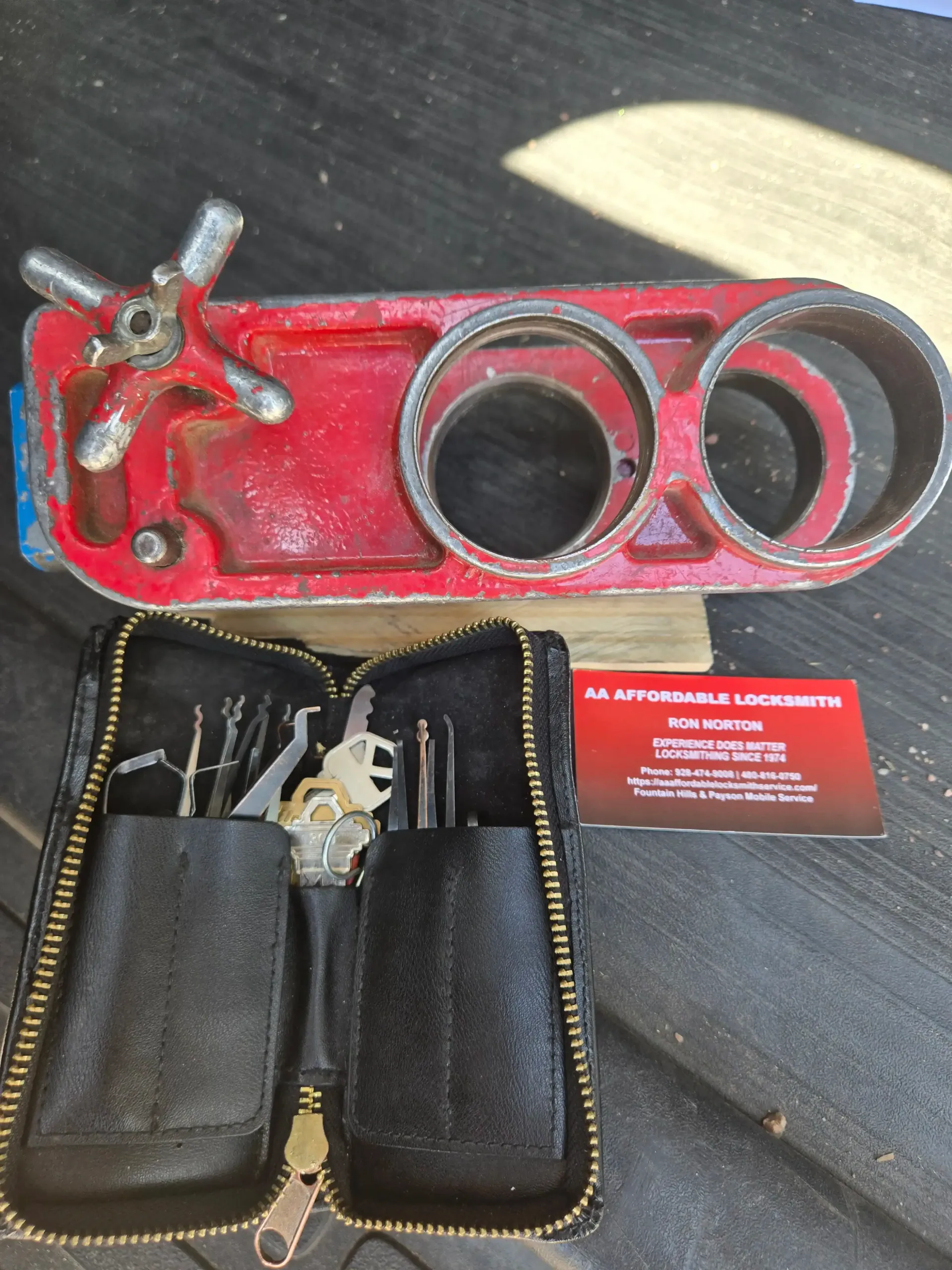 Red folding pipe cutter with black case and red business card on a dark surface.