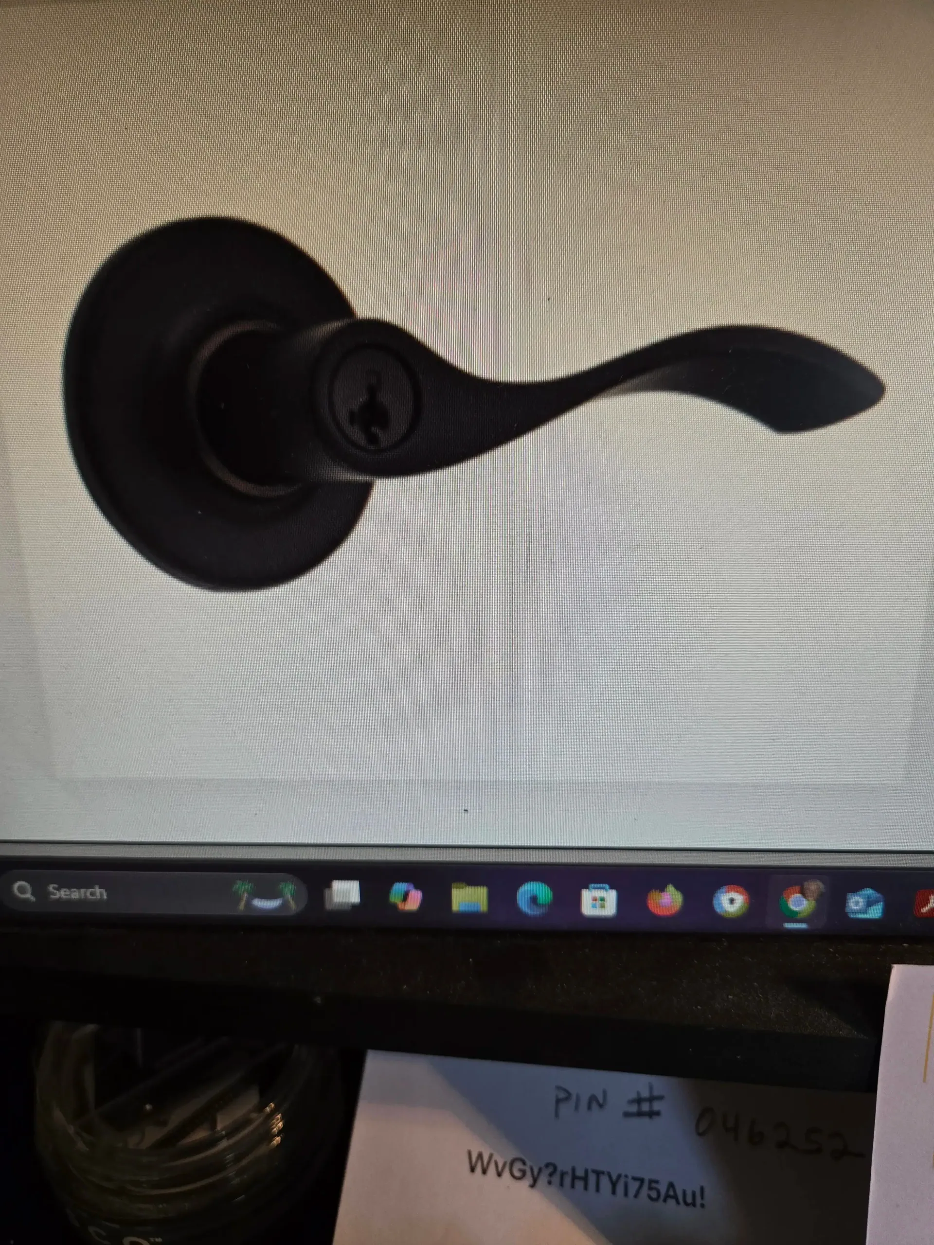 Black door lever handle on a dark round backplate against a textured silver wall.