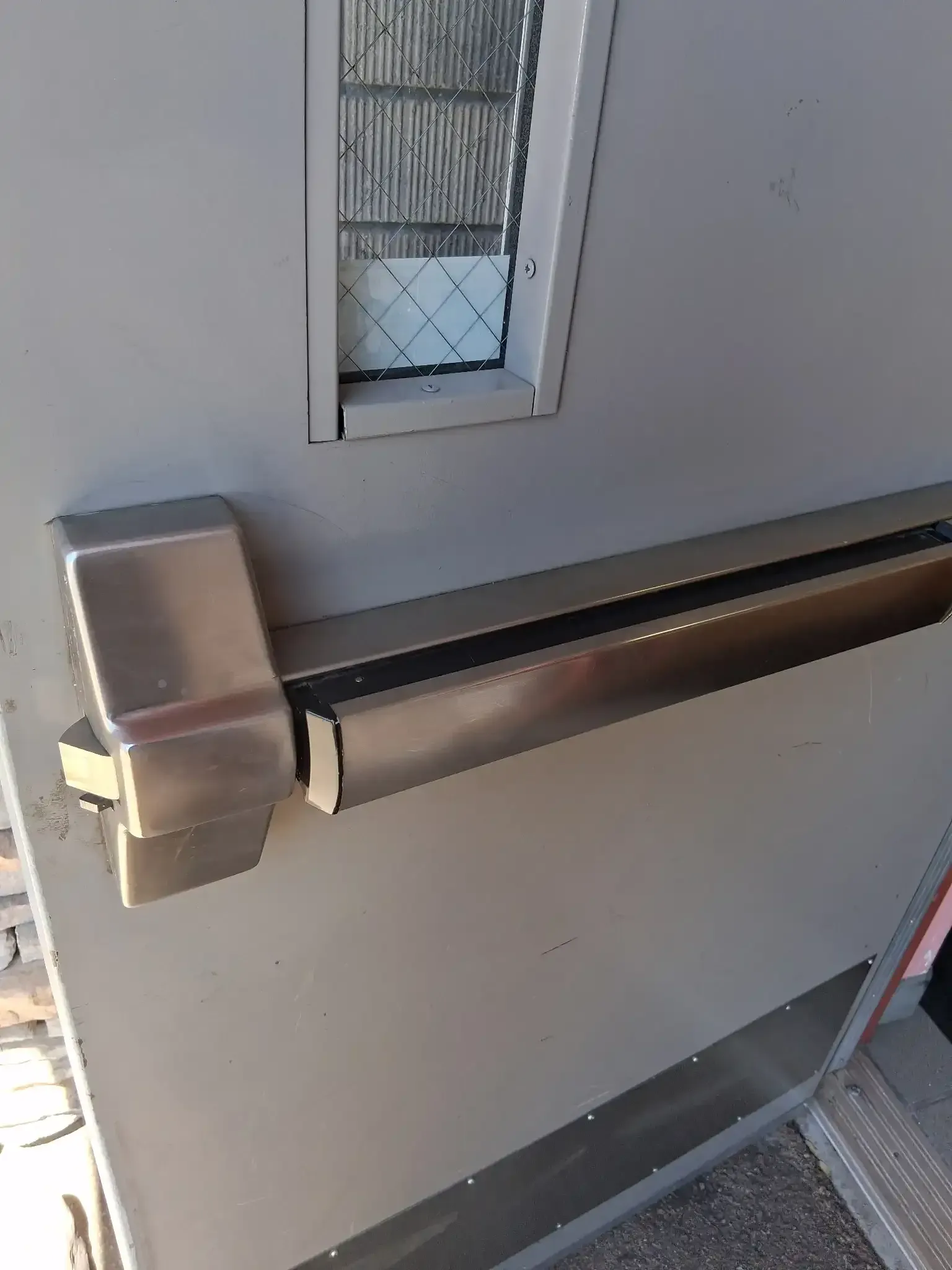 Close-up of a gray door with a metal lever handle and lock plate.