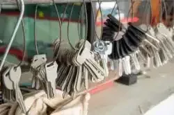 Row of hanging keychains with cartoon animal faces and striped straps on a shelf