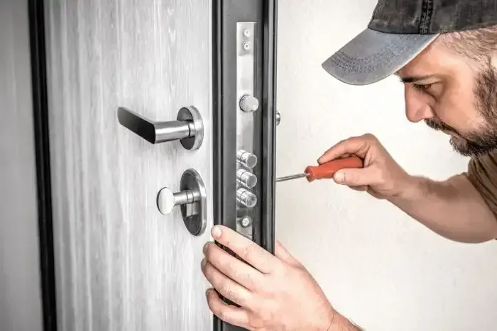 Technician repairing a silver front door lock with a screwdriver