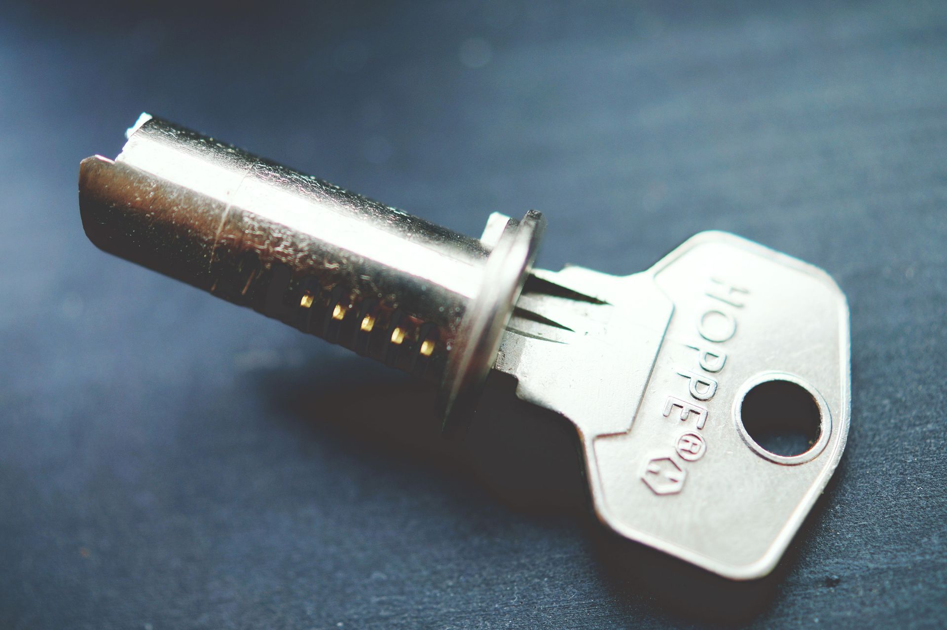 Silver key on a dark surface, with a small round head and a hole for a keyring.
