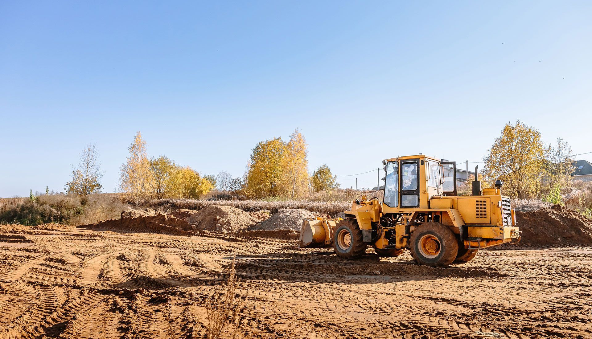 A yellow bulldozer is driving through a dirt field.