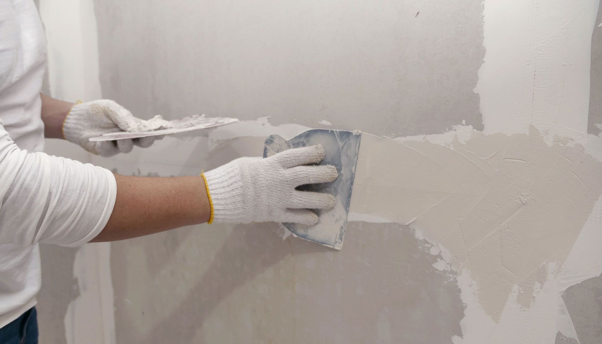 A man is plastering a wall with a spatula.