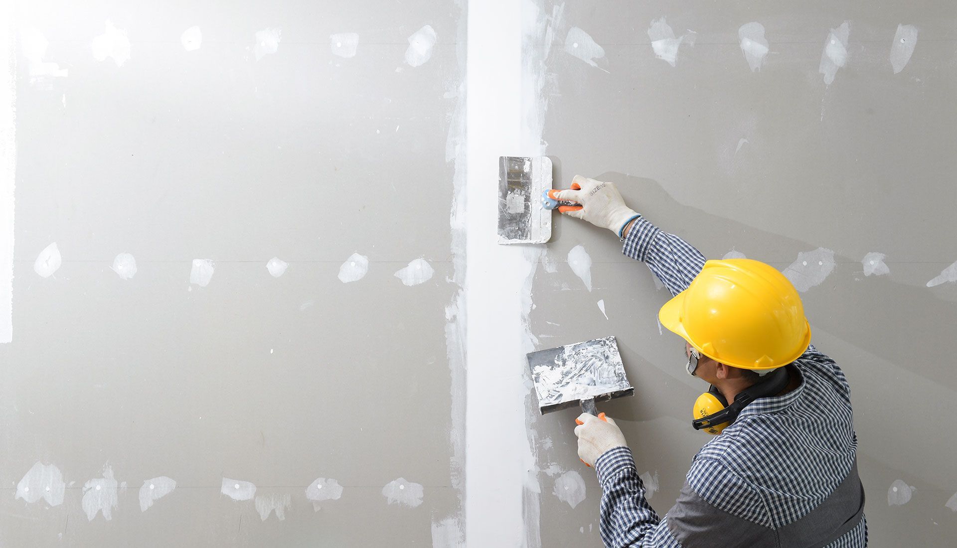 A man is plastering a wall with a trowel.