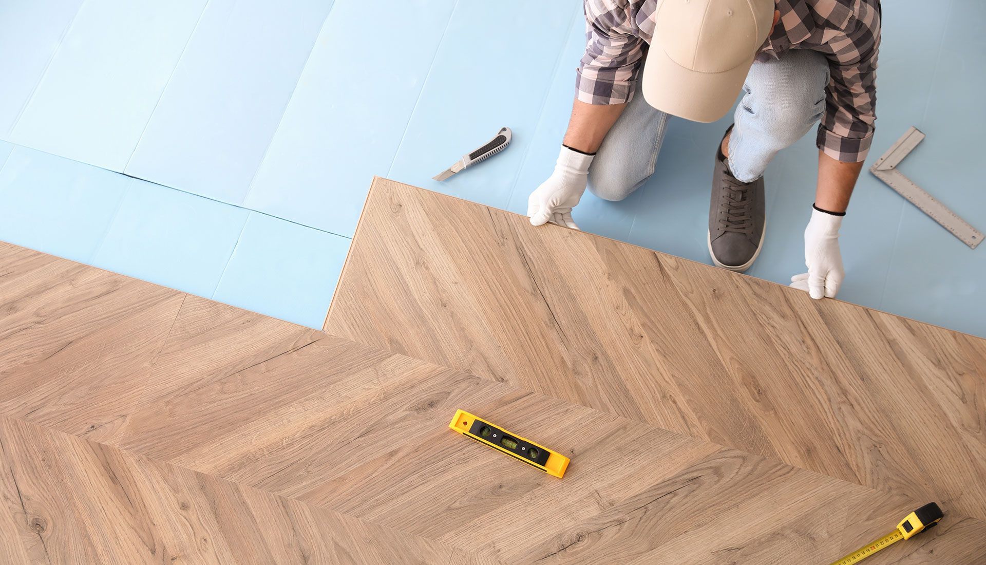 A man is installing a wooden floor in a room.