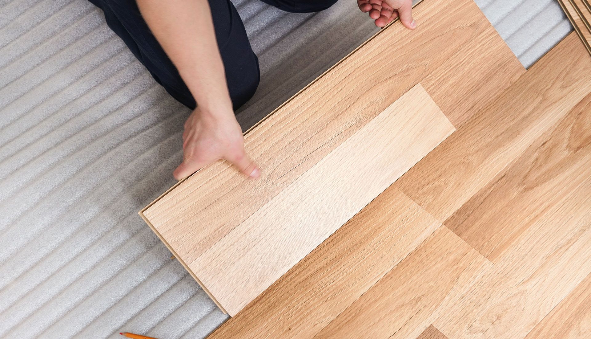 A person is installing a wooden floor in a room.
