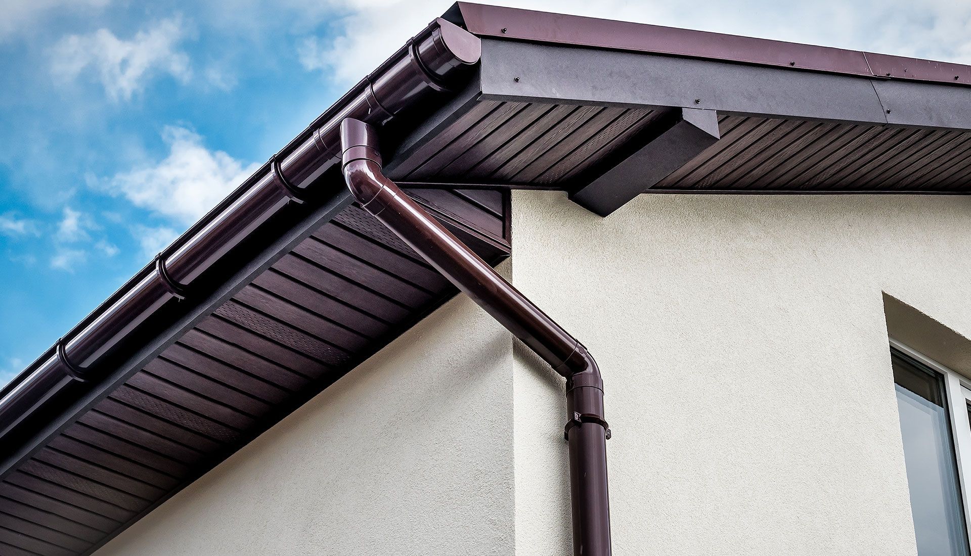 A house with a brown gutter on the side of it.