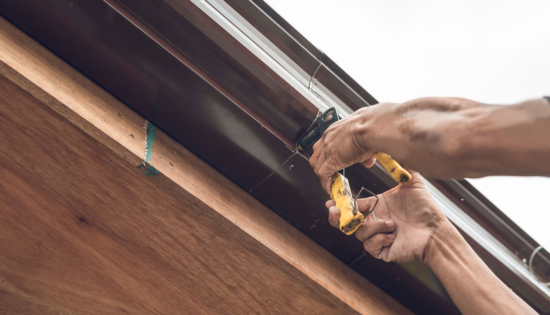 A person is installing a gutter on a wooden roof.