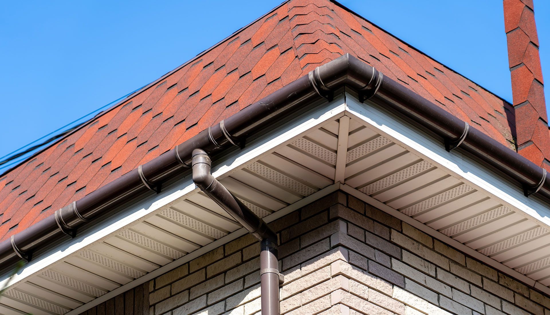 A close up of a gutter on the side of a house.