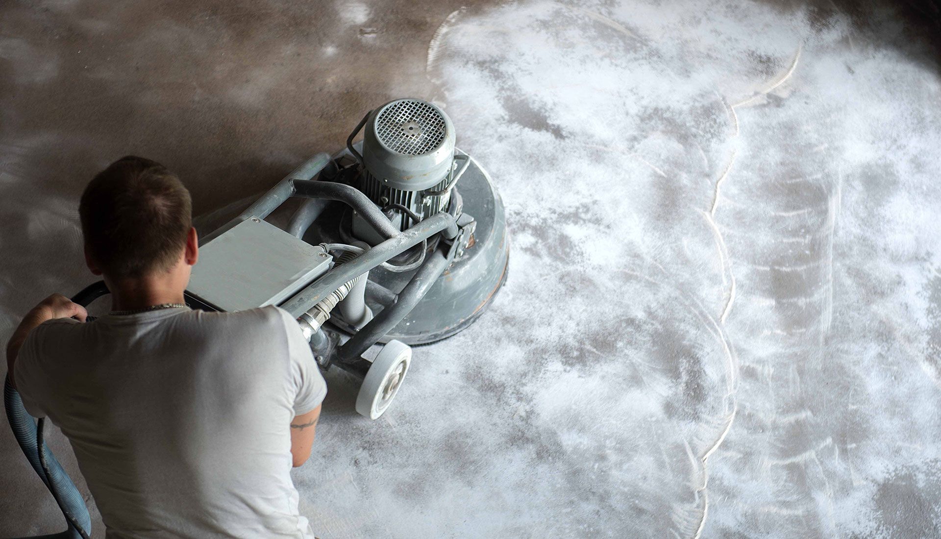 A man is using a machine to polish a concrete floor.