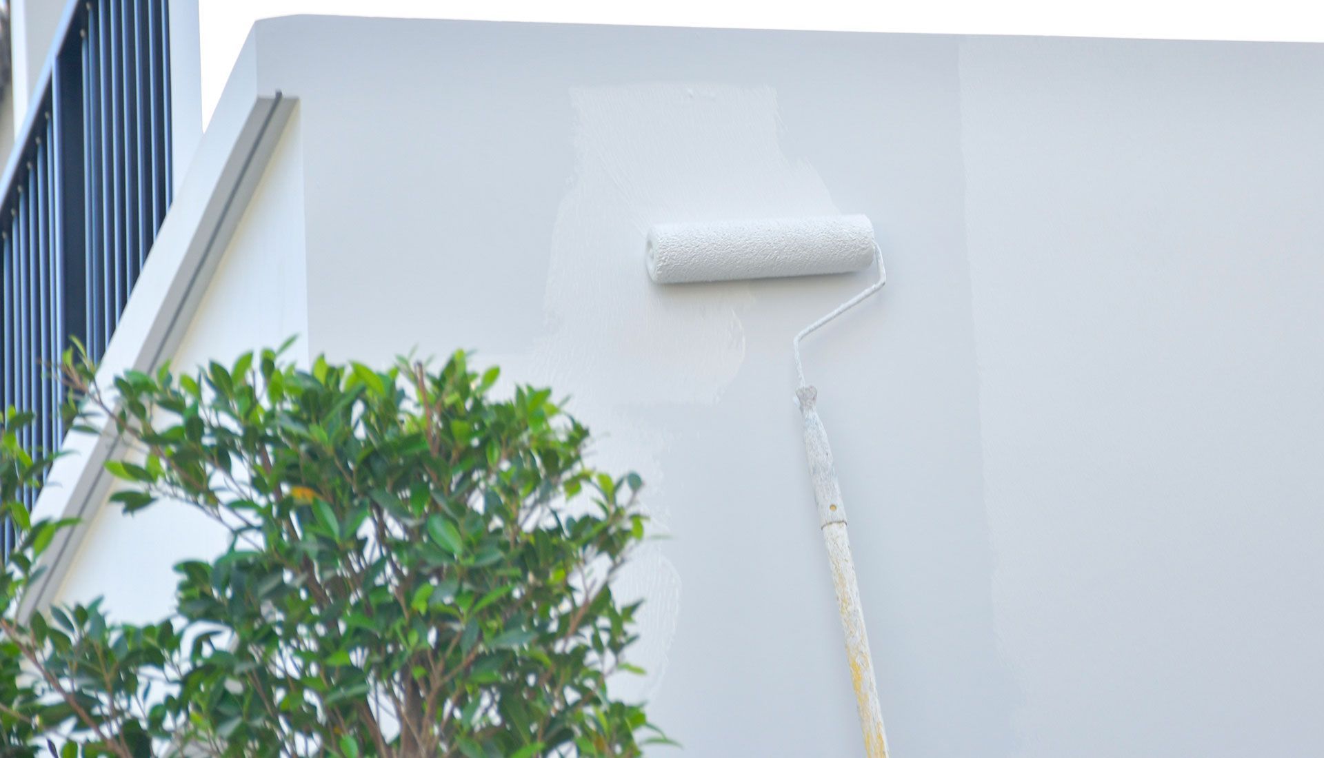 A person is painting a white wall with a roller.