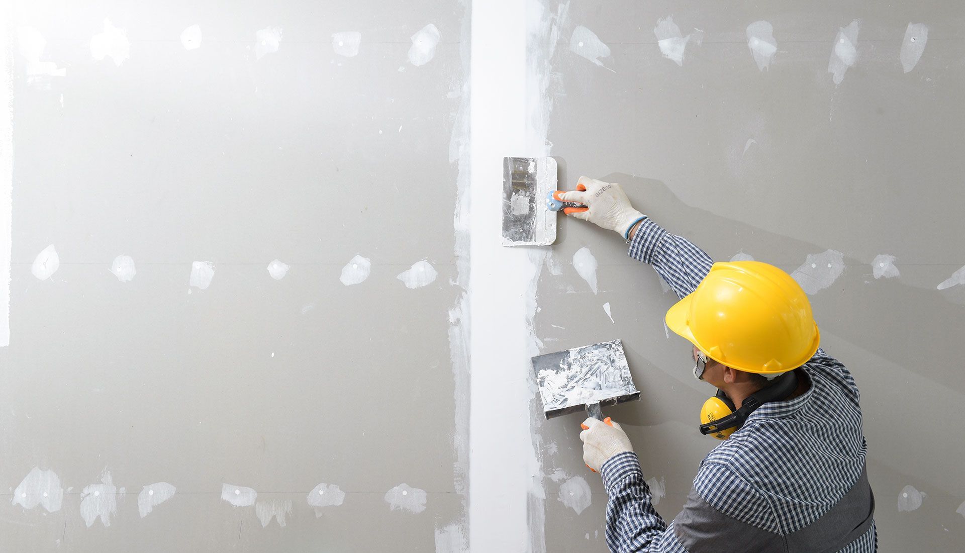 A man is plastering a wall with a spatula.