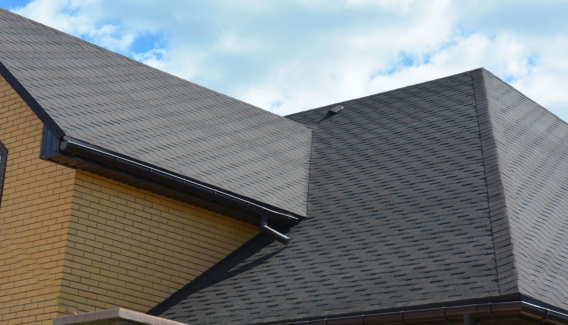 A close up of a roof of a house with a blue sky in the background.
