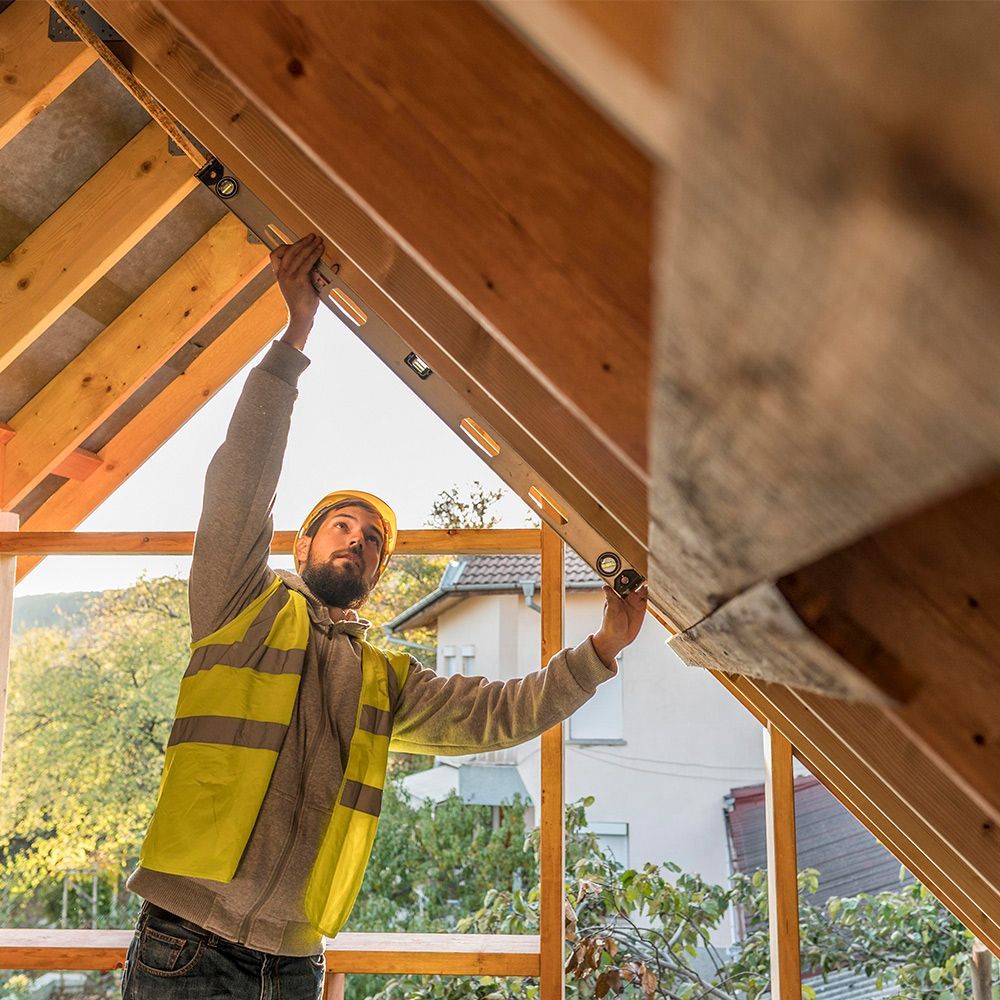 A man is using a level to check the level of a wooden structure.