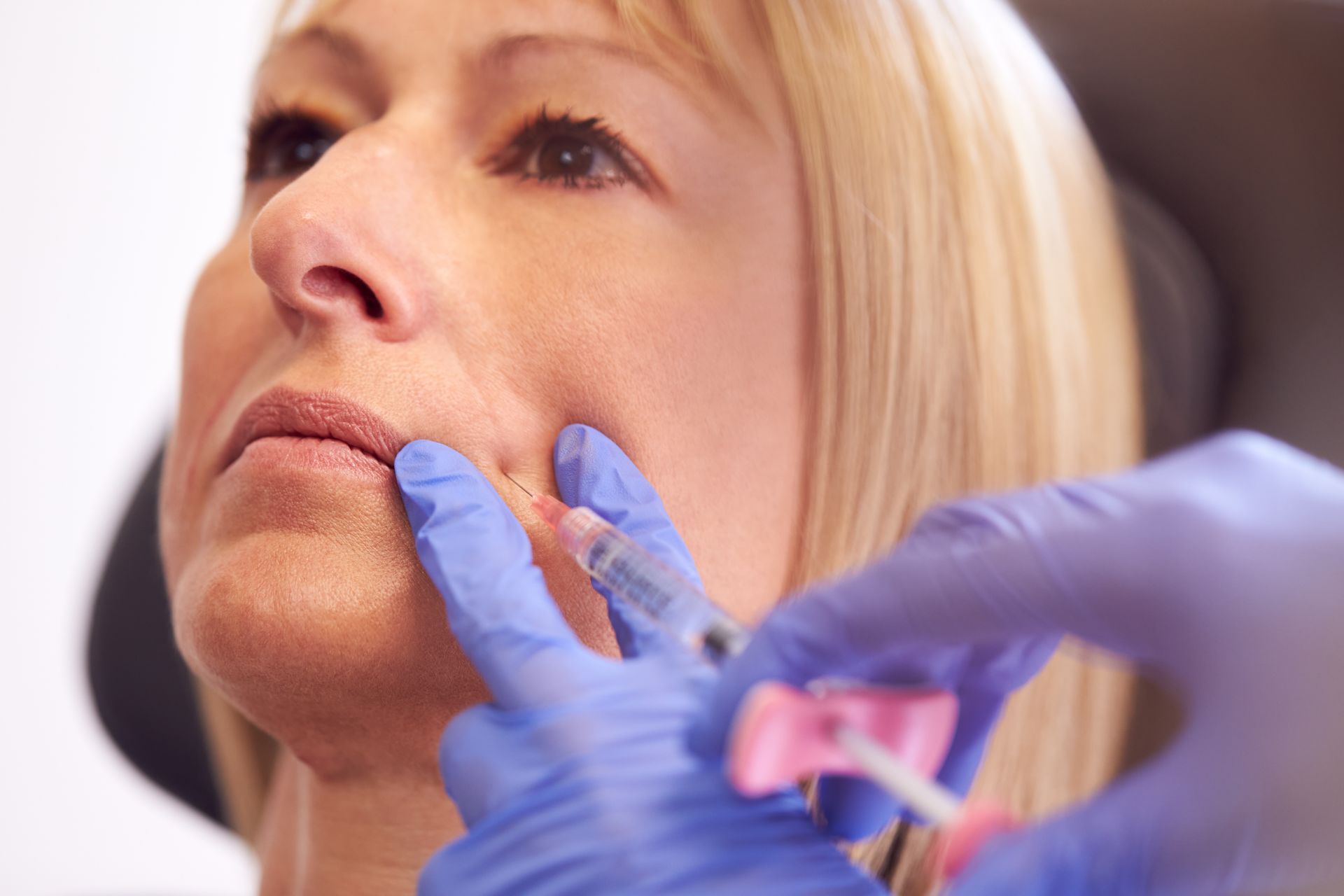 A woman is getting a botox injection in her lips.