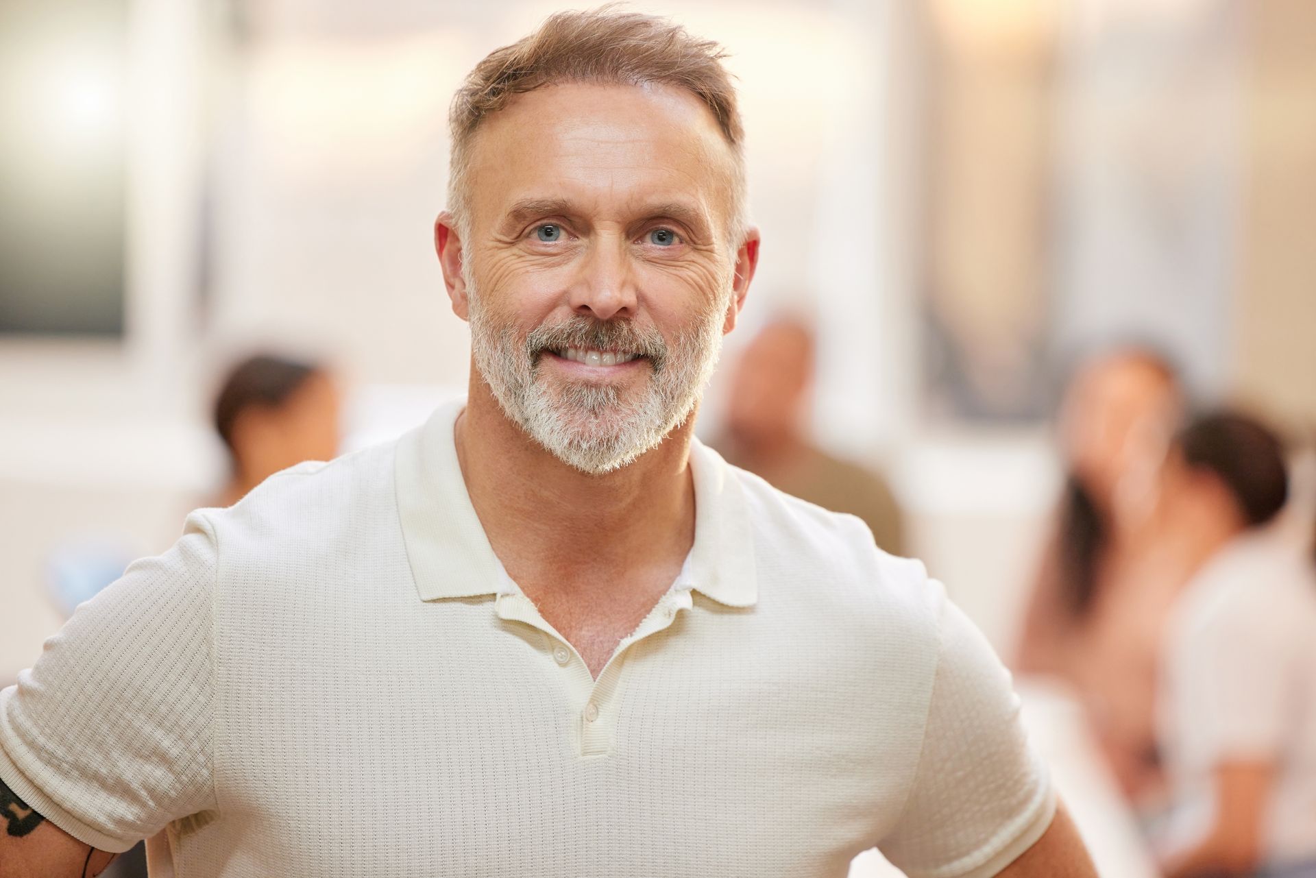 A man with a beard and a white shirt is smiling for the camera.