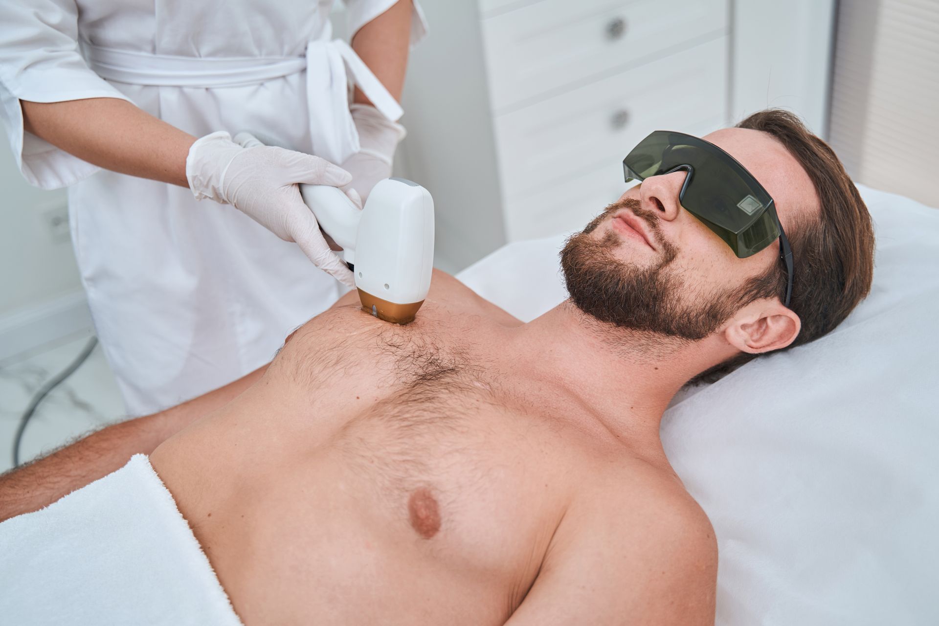 A man is getting a laser hair removal treatment on his chest.