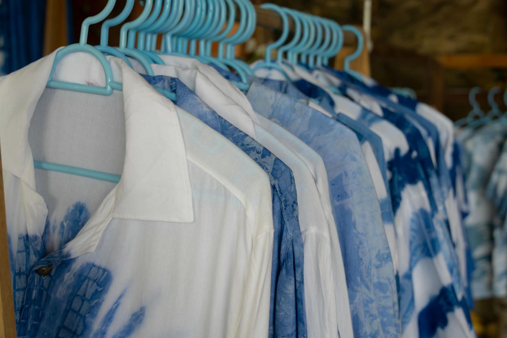 A row of blue and white shirts hanging on blue hangers.