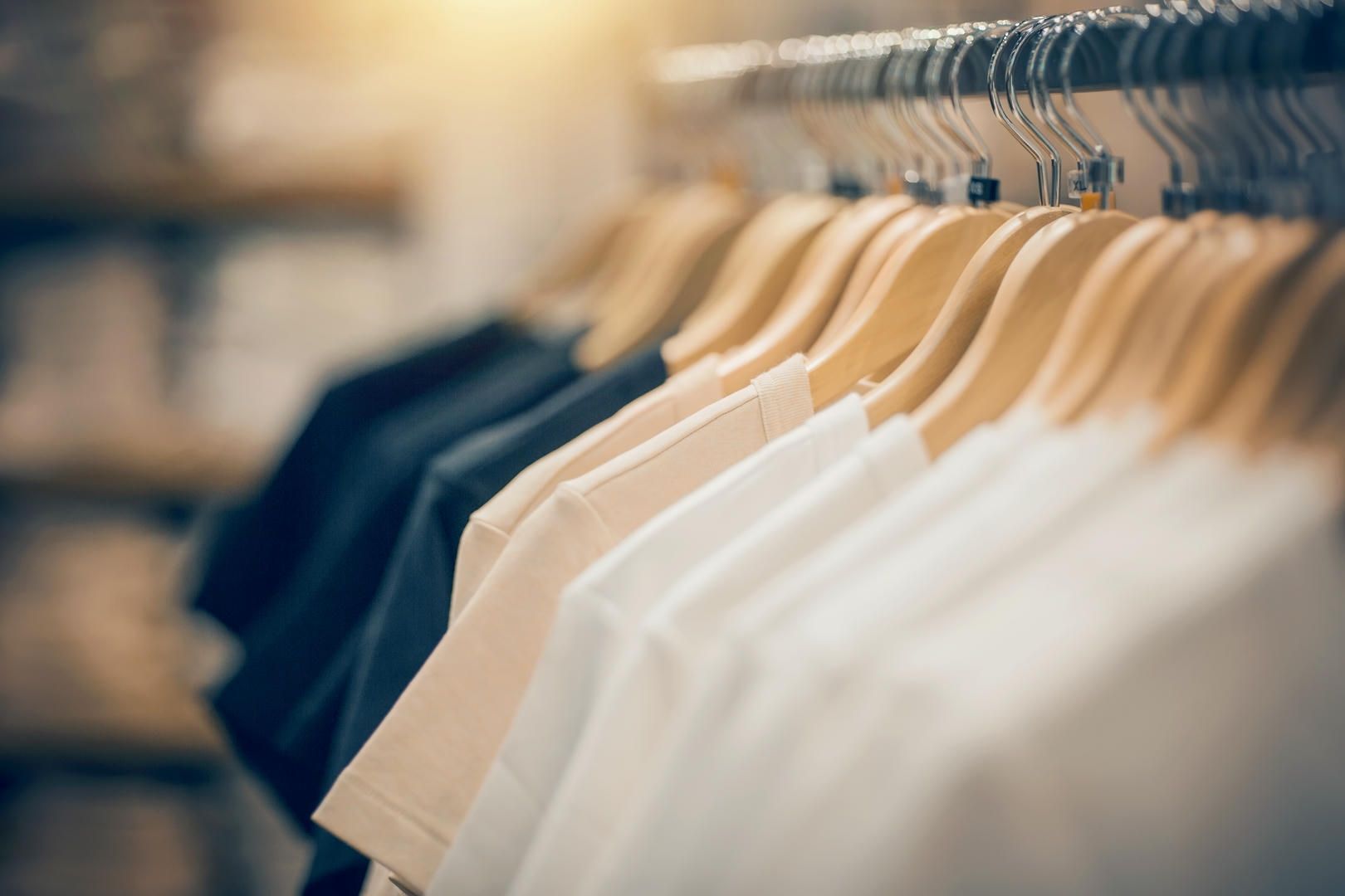A row of t-shirts hanging on a rack in a store.