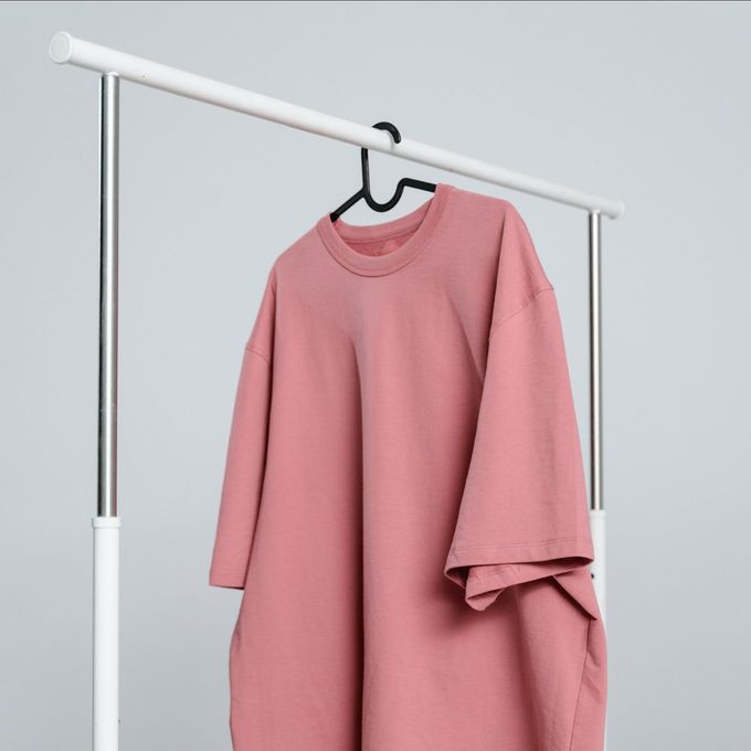 A pink t-shirt is hanging on a rack