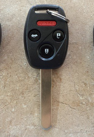 Black car key fob with buttons, silver key blade, and key ring.