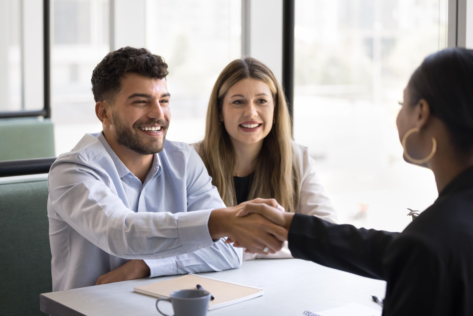 a man and woman are shaking hands with a woman at a table
