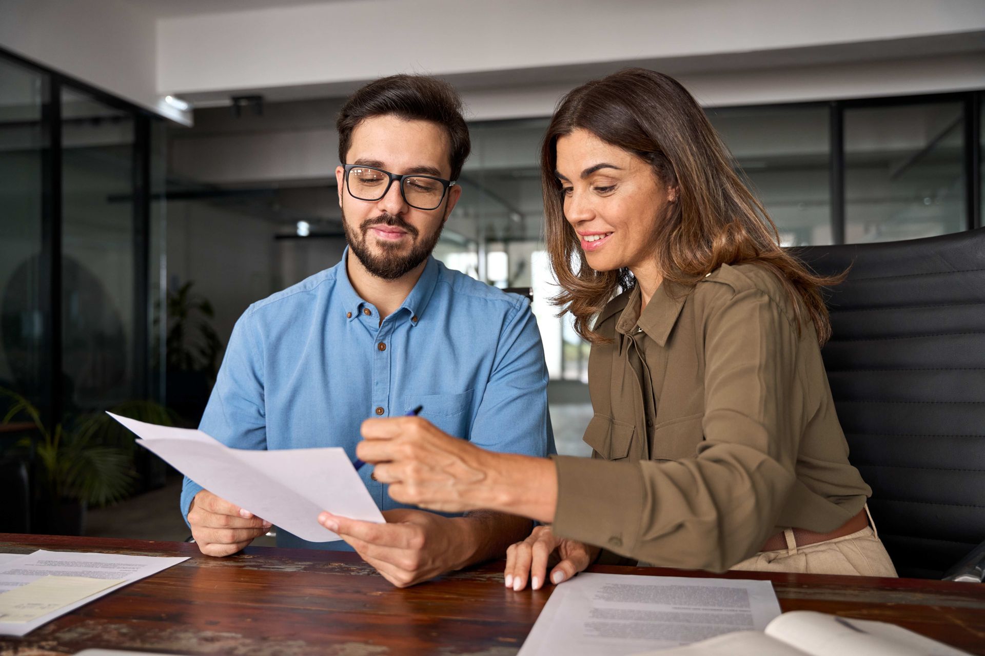 a man and a woman are sitting at a table looking at a piece of paper