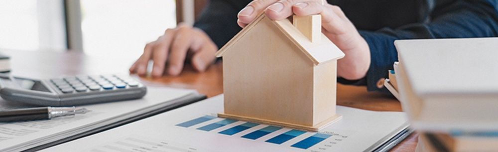 a person is holding a model house on top of a table