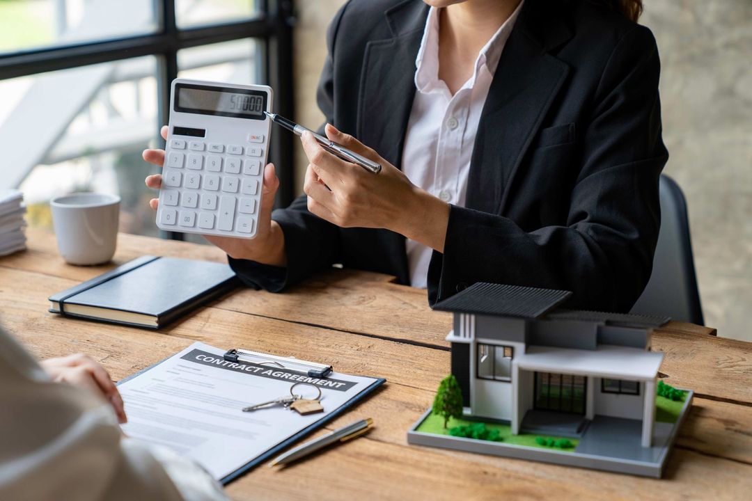a woman is sitting at a table holding a calculator and a pen