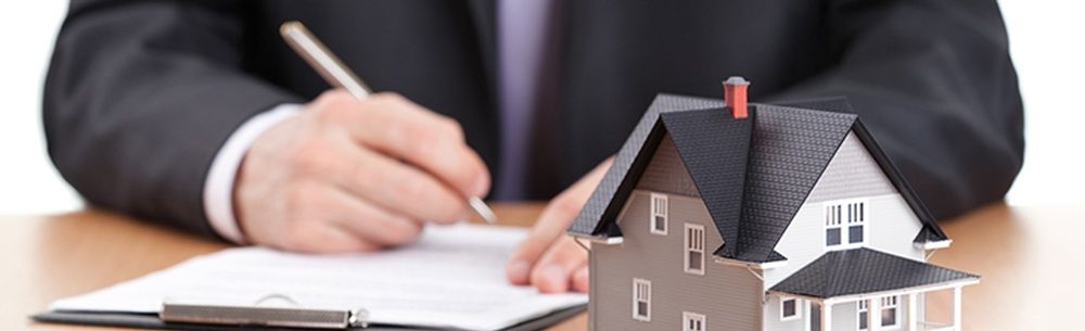 a man in a suit is signing a document next to a model house