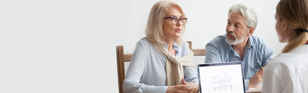 an elderly couple is sitting at a table talking to a doctor