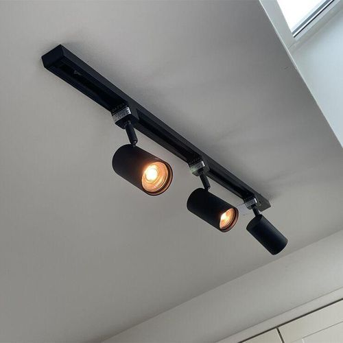 Black track lighting fixture with three adjustable spotlights on a white ceiling.