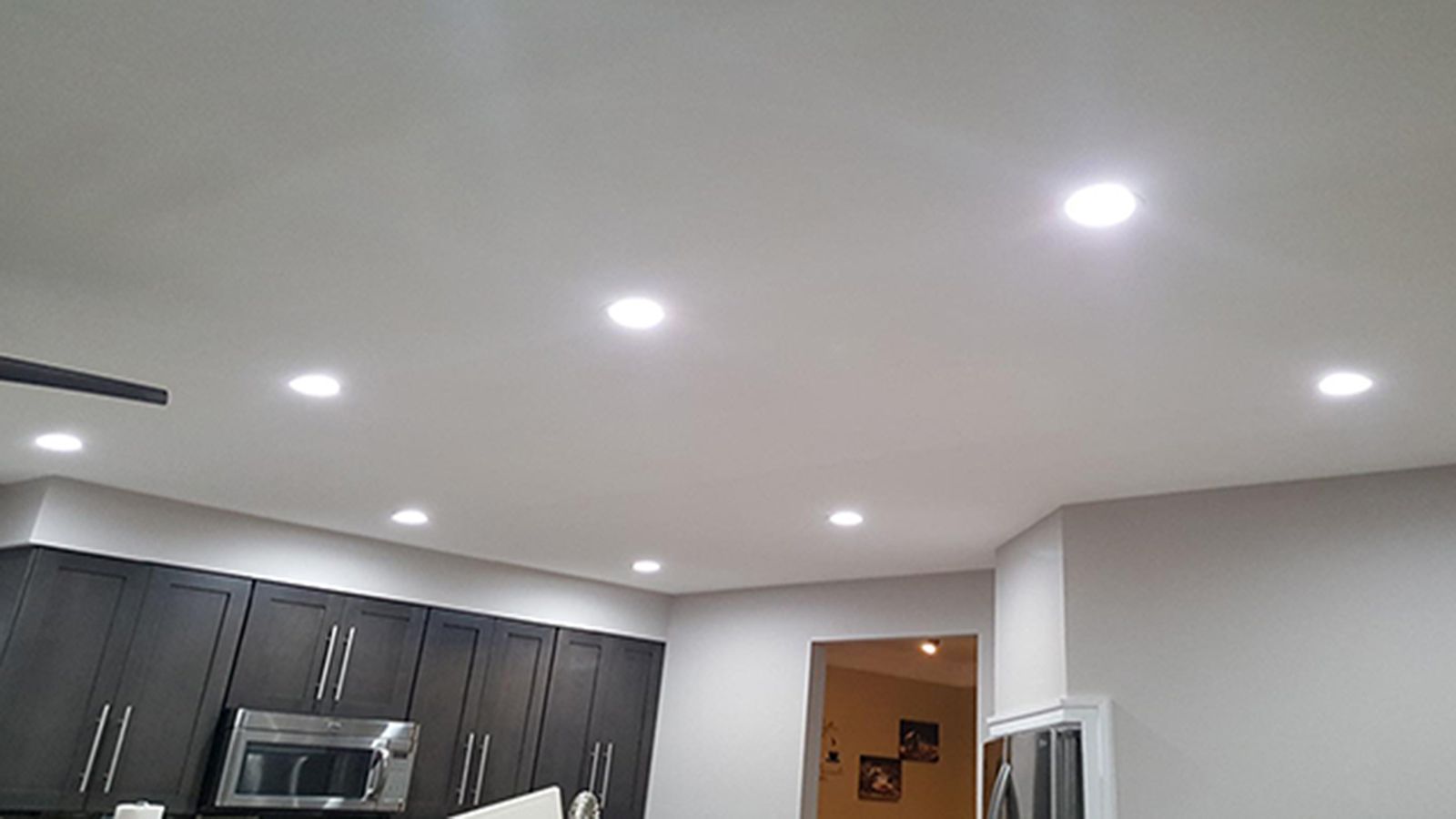Ceiling with recessed lights in a kitchen, cabinets below, neutral color scheme.