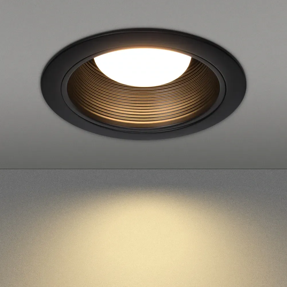 Black recessed can ceiling light emitting warm light.