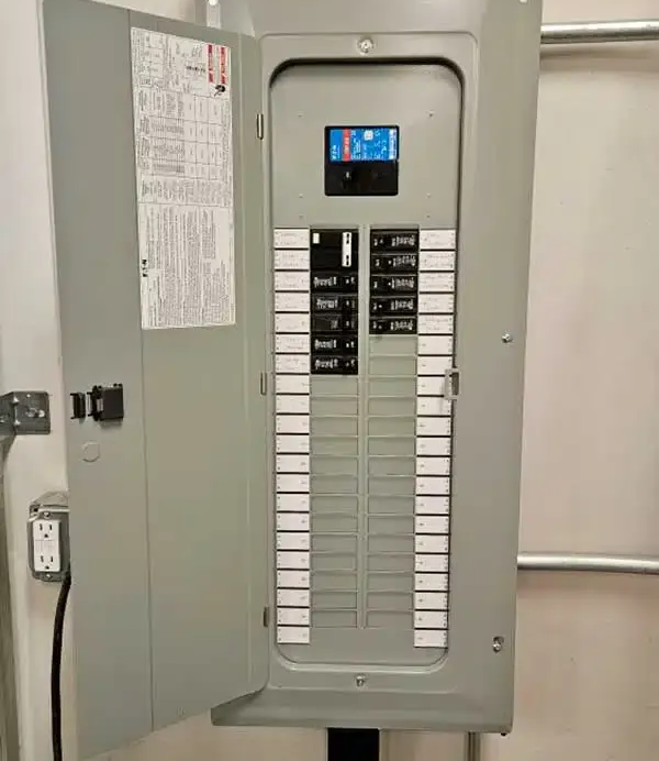 Opened electrical panel with circuit breakers. Gray metal box mounted on a wall.
