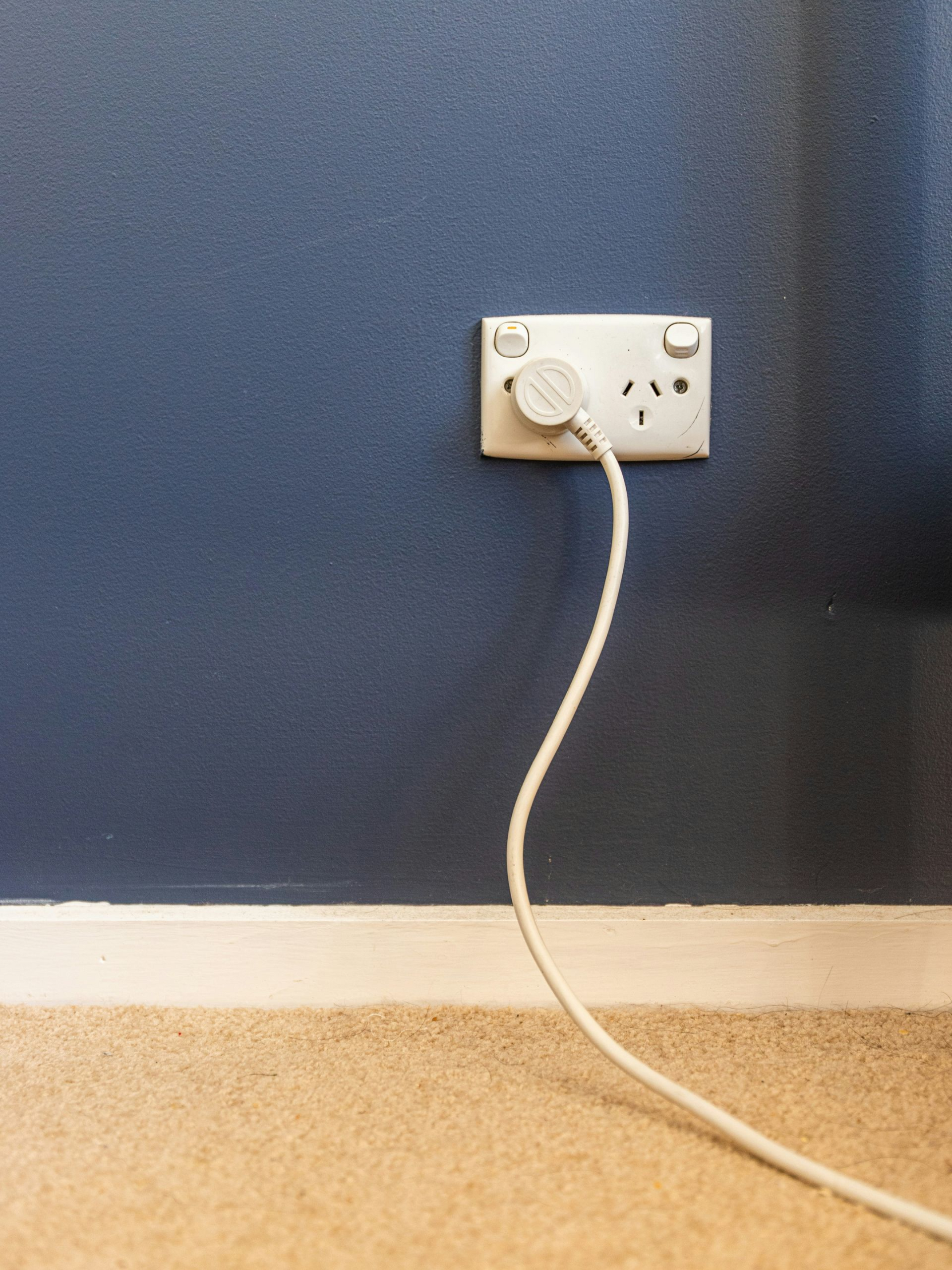 A beige Generac standby generator positioned outdoors in front of blue siding and a small window.