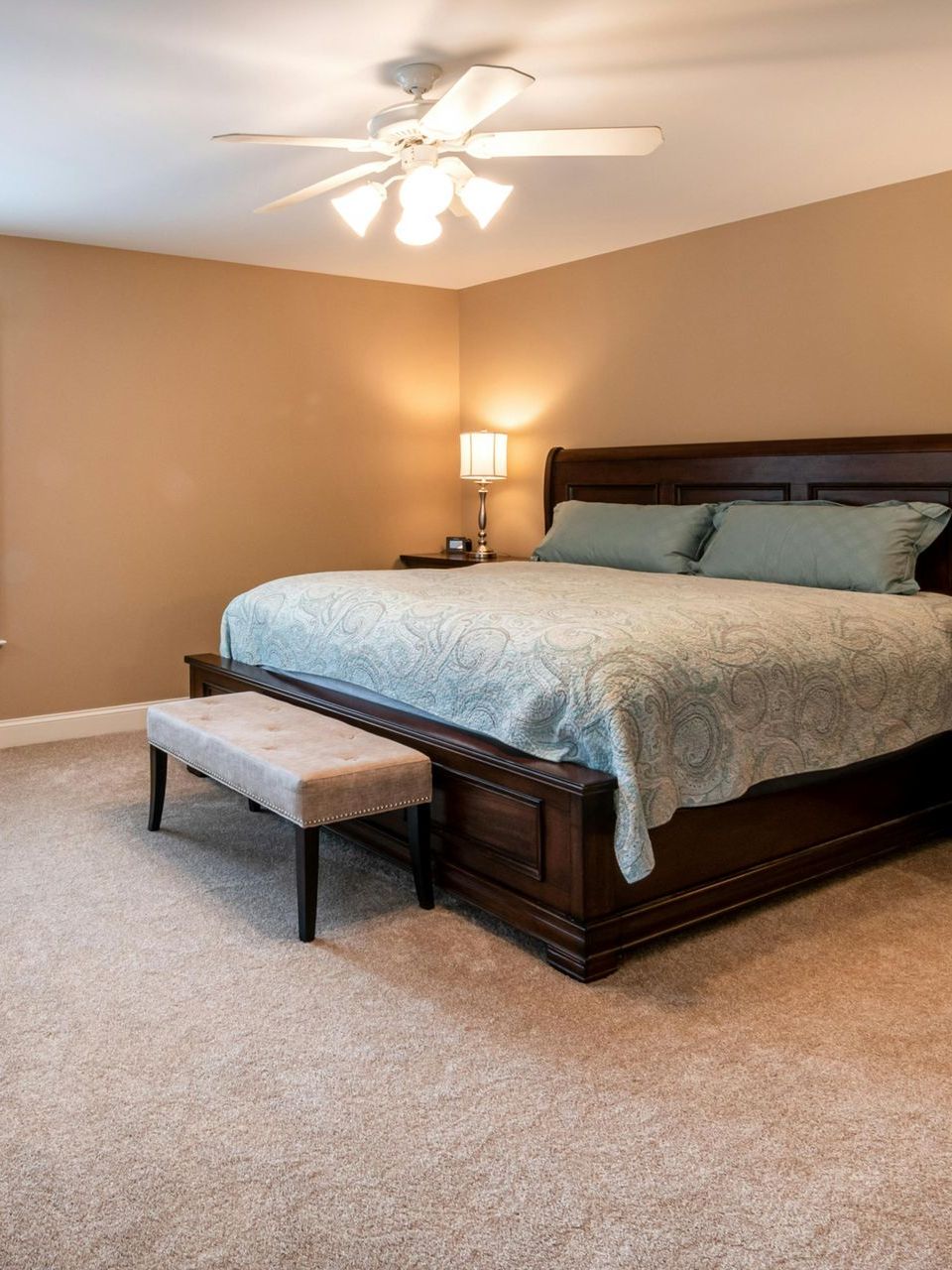 A bedroom with a large bed and a ceiling fan.