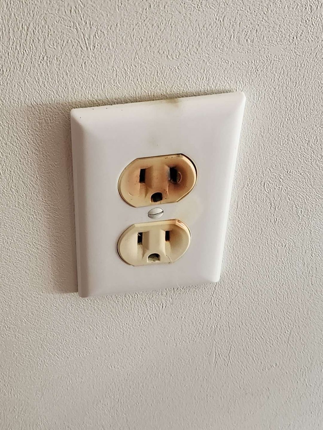 Burnt electrical outlet on a white wall.