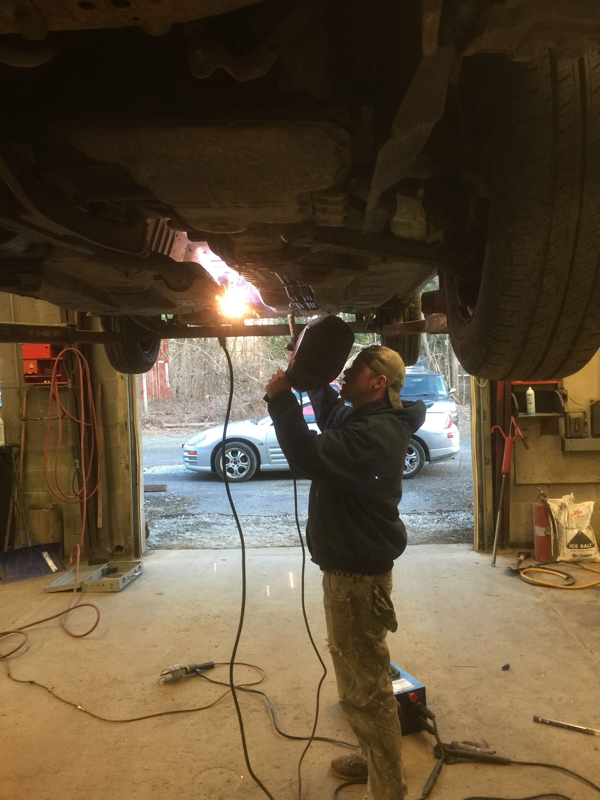Technician Performing Undercarriage Inspection in Garage | Abbott Automotive & Tire