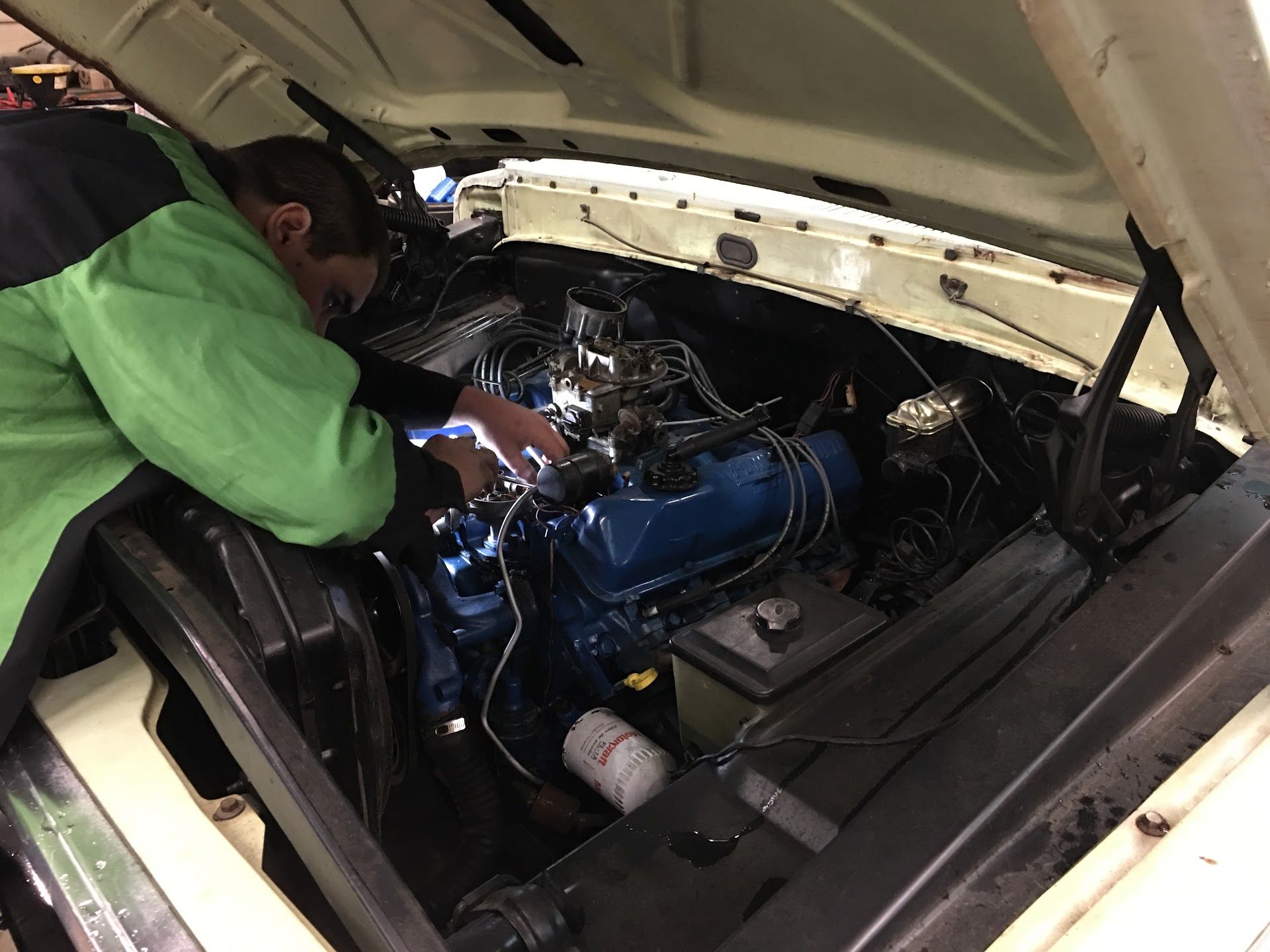 Mechanic in Green Jacket Repairing Engine Bay of a Classic Car | Abbott Automotive & Tire