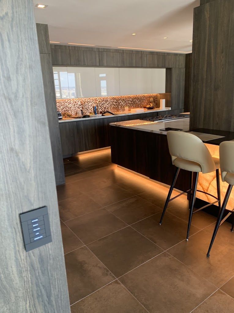 A kitchen with a large island and stools and a light switch on the wall.
