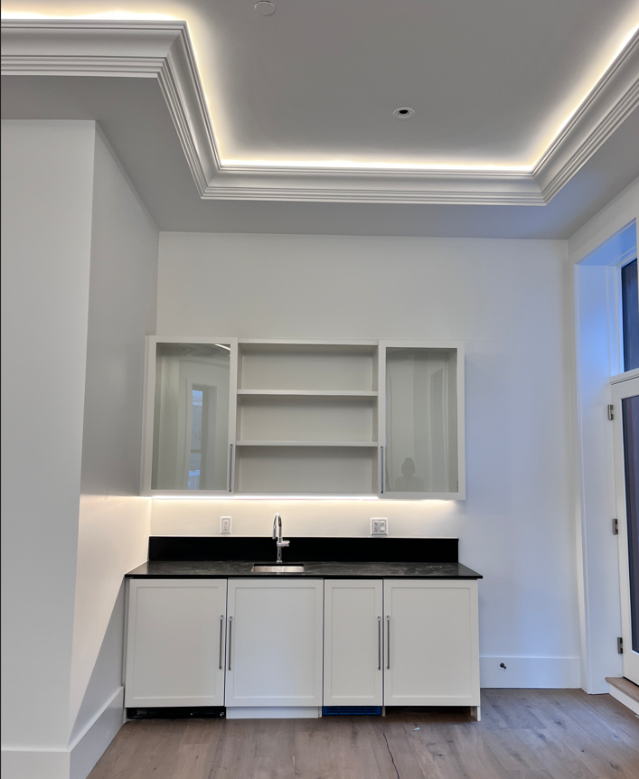 An empty kitchen with white cabinets and a sink