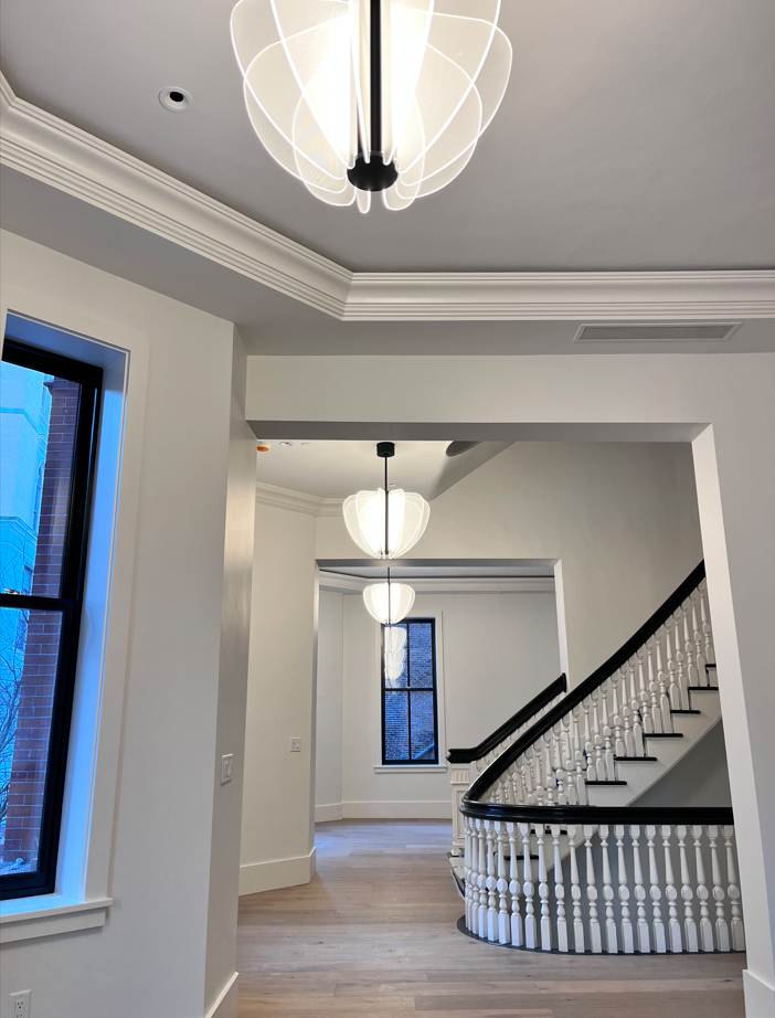 A hallway with stairs and a chandelier hanging from the ceiling