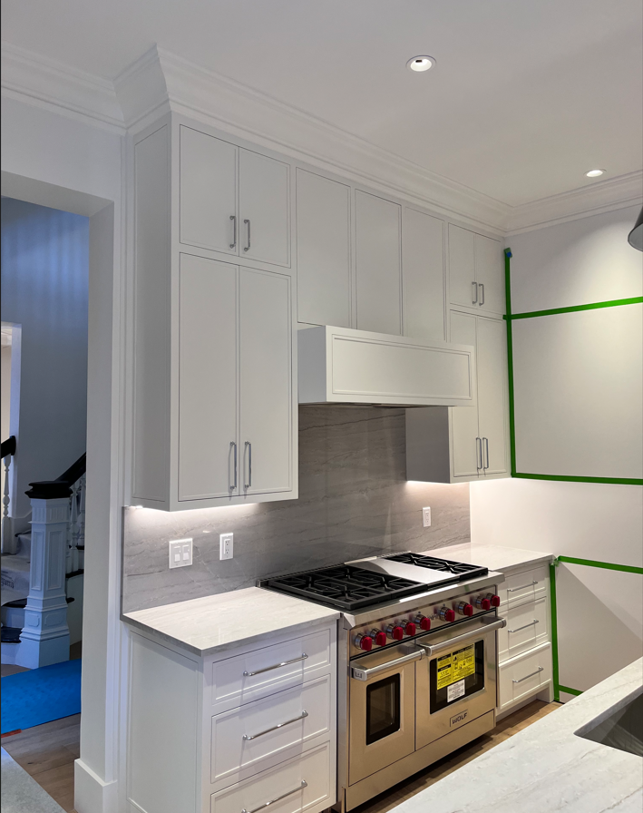 A kitchen with white cabinets , a stove , and a sink.