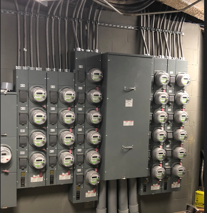 A bunch of electrical meters are hanging on a wall.