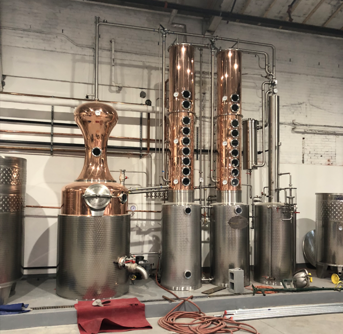 A row of copper and stainless steel containers in a factory