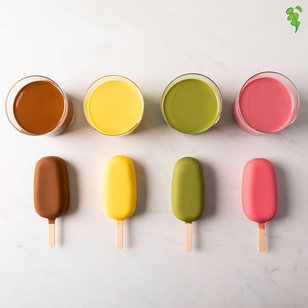 Una fila di quattro ghiaccioli colorati e le relative bevande: marrone, giallo, verde e rosa.